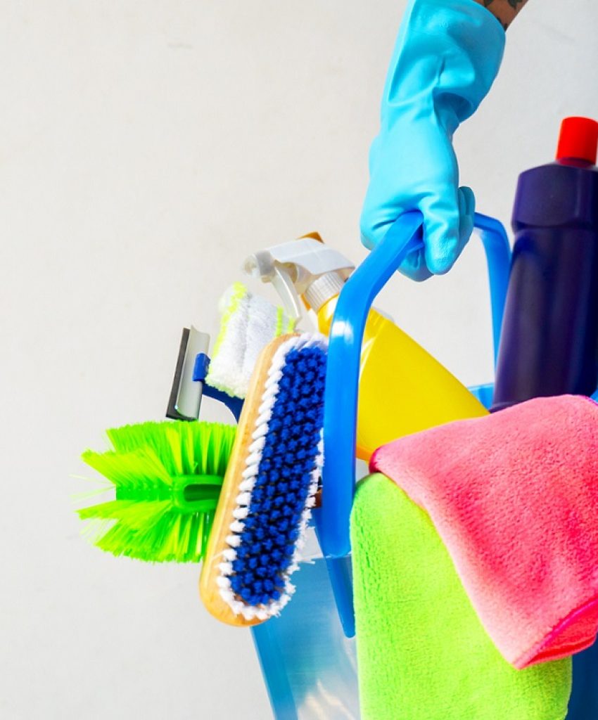 Man holding mop and plastic bucket with brushes, gloves and detergents in the kitchen